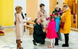 Klęczący mężczyzna wręcza podarunek dzieciom