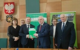 ludzie pozujący do zdjęcia z dokumentem oświadczającym przebudowe zbiornika wodnego