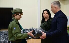 Kobieta i mężczyzna przekazujący paczkę dla harcerza