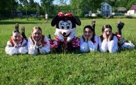 Dziewczyny w strojach ludowych pozują z osobą przebraną za Myszkę Minnie