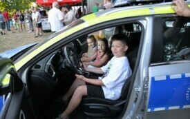 Troje dzieci pozuje do zdjęcia w wozie policyjnym