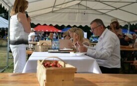 Ludzie jedzą pierogi z truskawkami, siedząc przy stole