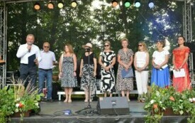 Siedem kobiet i dw&oacute;ch mężczyzn stoją na scenie