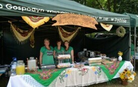 Trzy kobiety z Koła Gospodyń Wiejskich stoją przy stole z jedzeniem