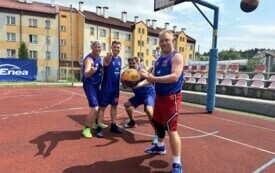 Grupa mężczyzn pozuje do zdjęcia przy koszu