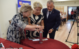 Troje ludzi wsadza list do kapsuły czasu