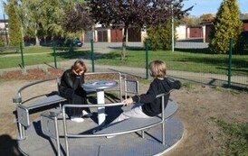 dwie osoby siedzą na okragłej huśtawce 