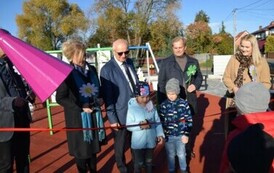 dw&oacute;jka dzieci na okrągłej huśtawce i kobieta huśtająca ich 