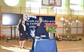 na zdjęciu widać burmistrza miasta i gminy Połaniec Jacka Nowaka, kt&oacute;ry zwraca się do pani dyrektor Małgorzaty Łukaszek szkoły w Ruszczy, na stoliku znajduje się bukiet z czerwonych r&oacute;ż oraz niebieski obrus