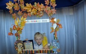 zdjęcie przedstawia chłopca pierwszoklasistę w dekoracyjnej ramce z napisem ślubowanie 2022, chłopiec trzyma akt pasowania ucznia