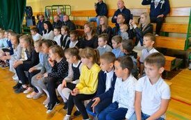 widok na grupę dzieci siedzacych na ławkach na sali 