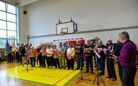 grupa ludzi z środowiskowego domu samopomocy, kt&oacute;ra śpiewa patriotyczną piosenkę