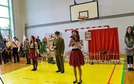 trzy osoby śpiewające, po środku chłopak w zielonym mundurze i zielonej czapce, a po prawej stronie i po lewej chłopca dziewczyny ubrane w g&oacute;ralskie stroje