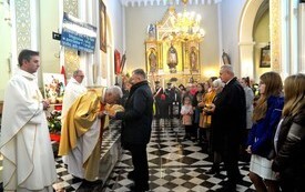burmistrz wraz z sekretarz podają księżom chleb