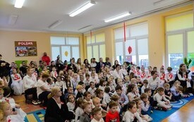 grupa przedszkolak&oacute;w, nauczycieli i rodzic&oacute;w oglądających występ
