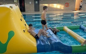 Dzieci na basenie w Połańcu na dmuchanym torze przeszk&oacute;d ustawionym w ramch ferii na sportowych