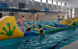 Dzieci na basenie w Połańcu na dmuchanym torze przeszk&oacute;d ustawionym w ramch ferii na sportow