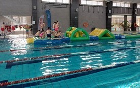 Dzieci na basenie w Połańcu na dmuchanym torze przeszk&oacute;d ustawionym w ramach ferii na sportowo