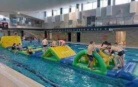 Dzieci na basenie w Połańcu na dmuchanym torze przeszk&oacute;d ustawionym w ramach ferii na sportowo