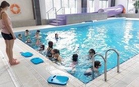 Dzieci na małym basenie ćwiczą z instruktorem