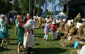 na zdjęciu grupa os&oacute;b tańczy obok wieńc&oacute;w dożynkowych