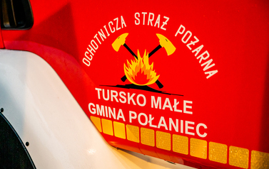 Na zdjęciu widać drzwi samochodu strażackiego w kolorze czerwonym z oznakowaniem Ochotniczej Straży Pożarnej w Tursku Małym. 